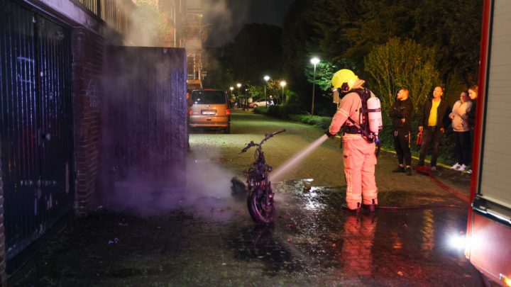 Scooter in brand tegen gevel flat